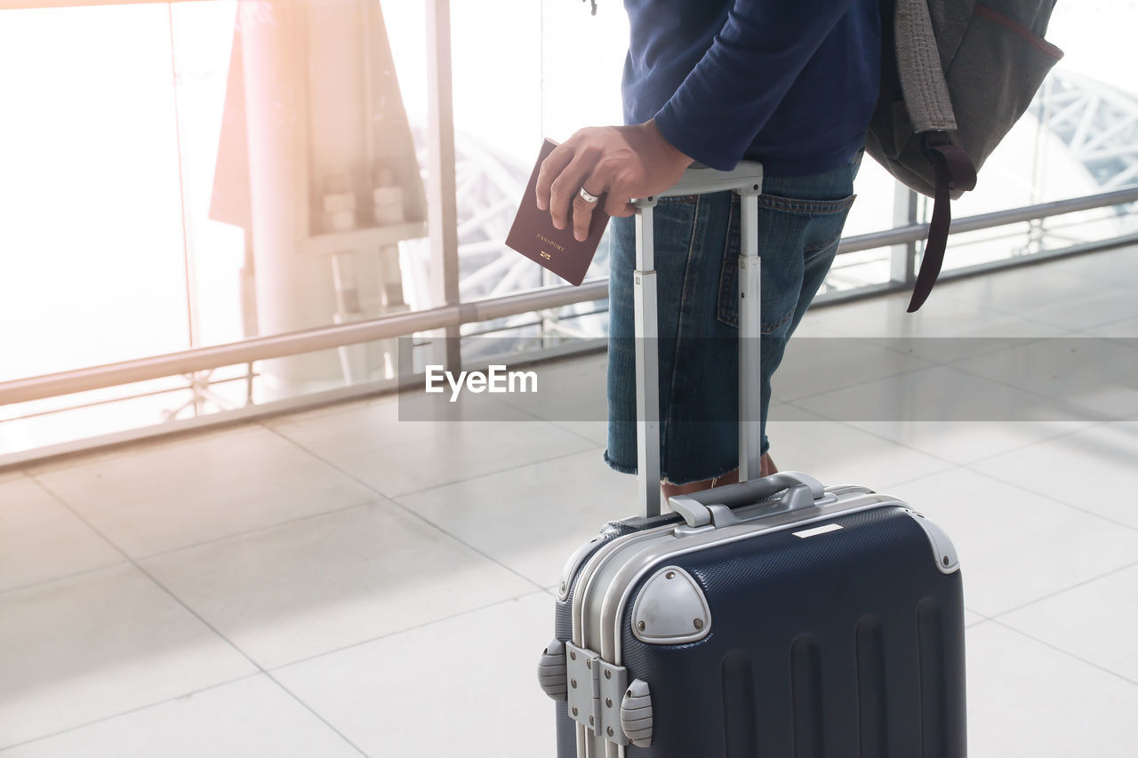 Midsection of man standing with suitcase