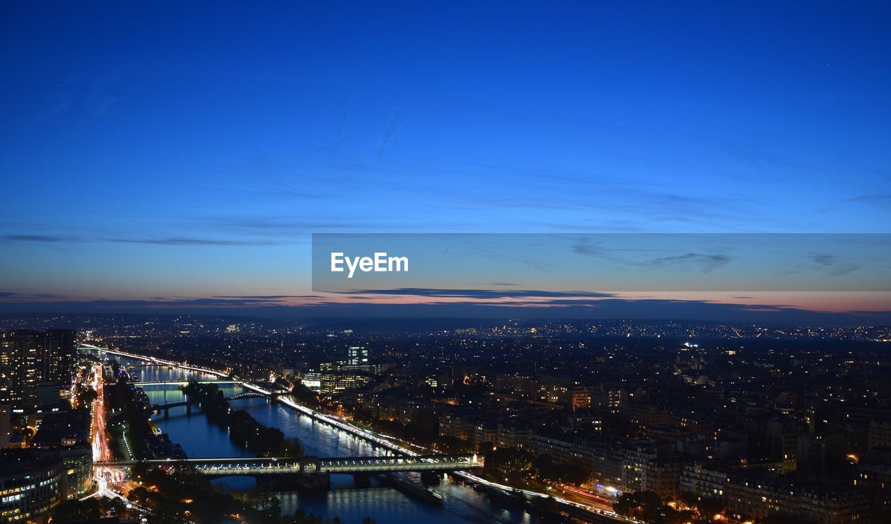 River amidst cityscape against sky at dusk