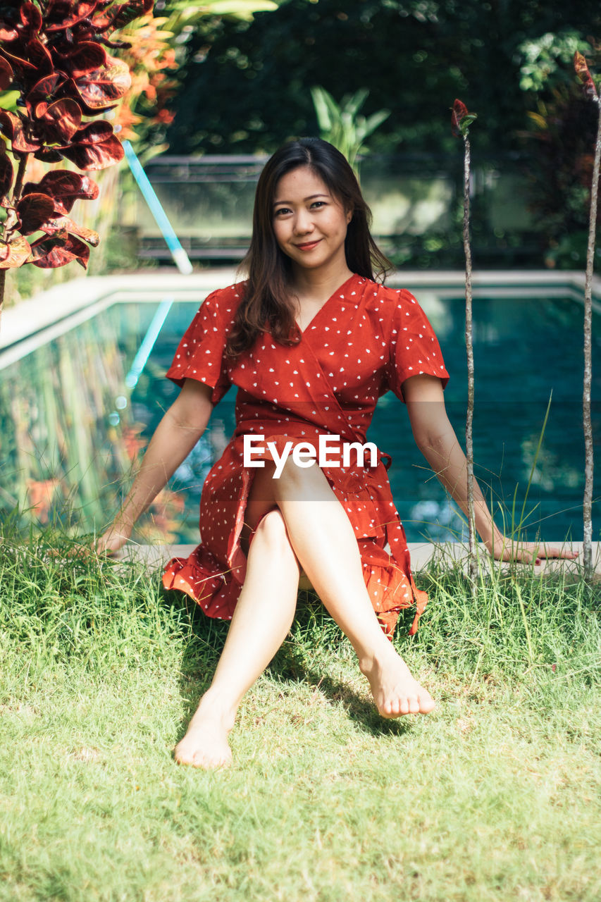 Portrait of woman sitting on land against swimming pool