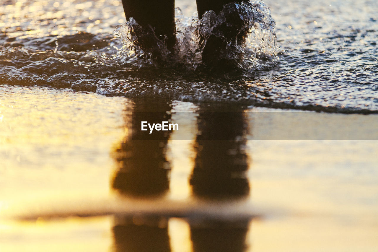 LOW SECTION OF MAN ON WET SAND