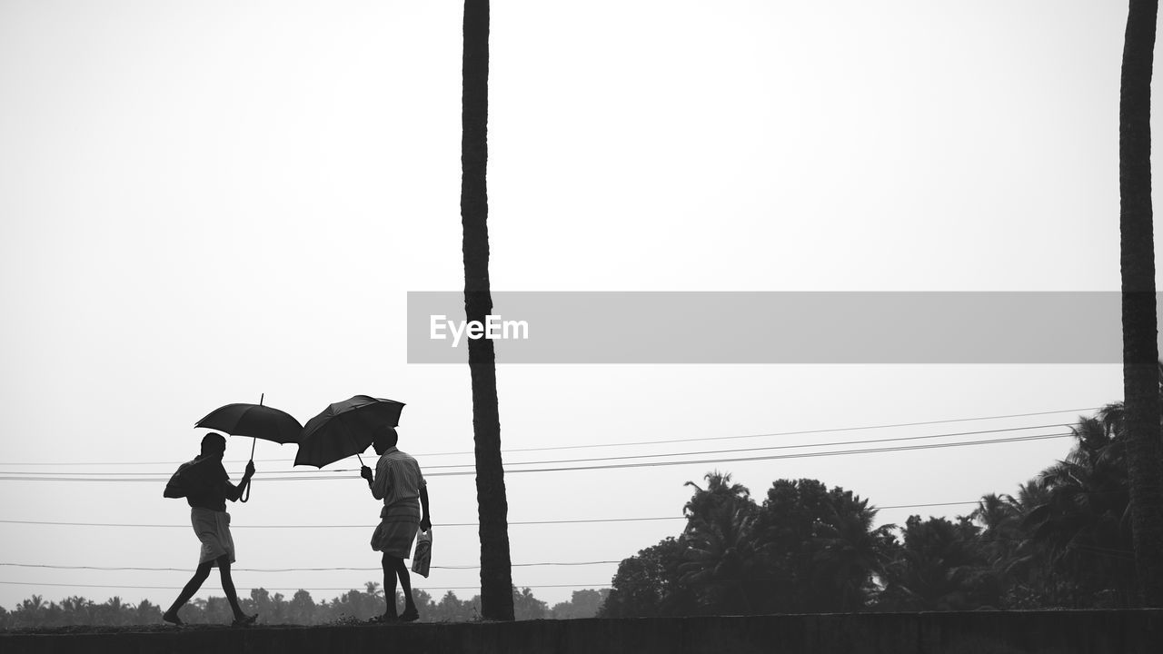 MAN AND WOMAN WALKING ON STREET AGAINST CLEAR SKY