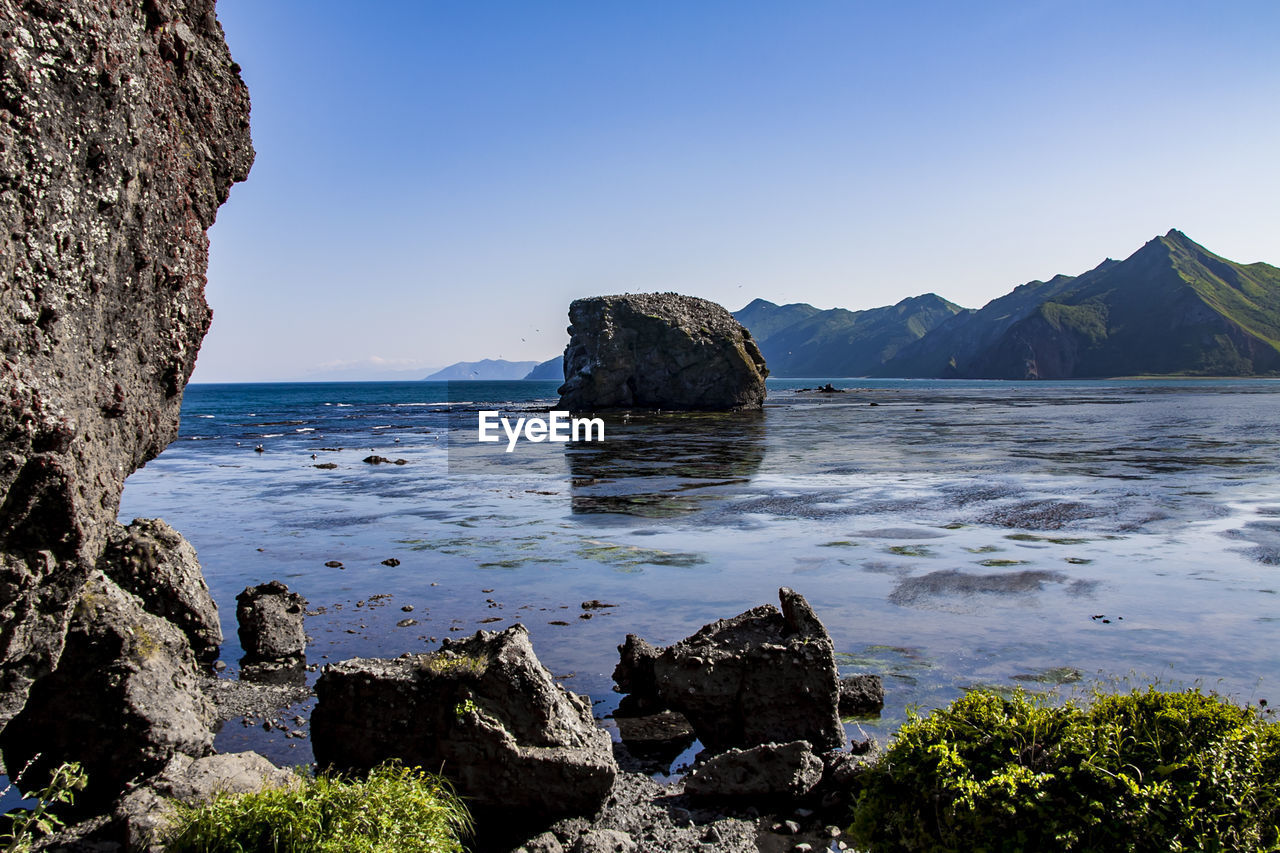 ROCKS IN SEA AGAINST CLEAR BLUE SKY