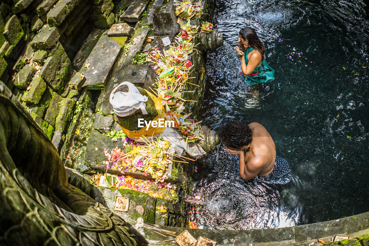 HIGH ANGLE VIEW OF MEN SWIMMING ON ROCK