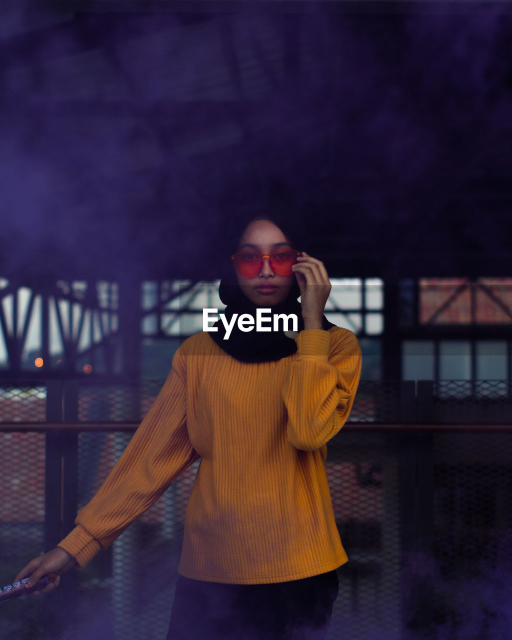 Portrait of young woman wearing sunglasses while standing amidst smoke