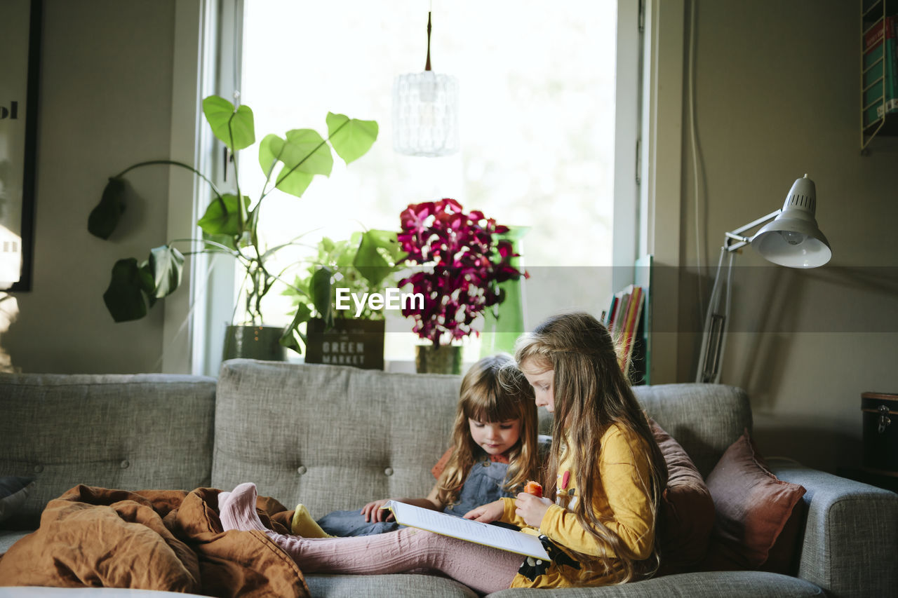 Sisters reading book on sofa