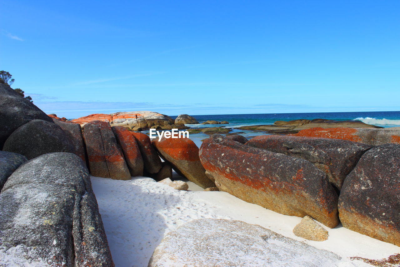 Rocks by sea against blue sky