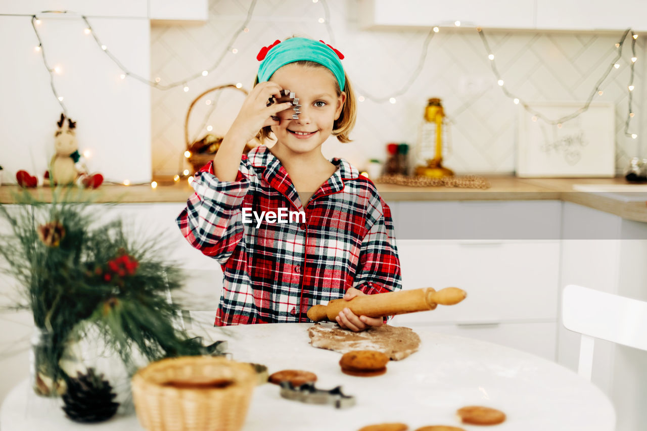A girl in a plaid shirt bakes christmas cookies on christmas eve or new year's eve