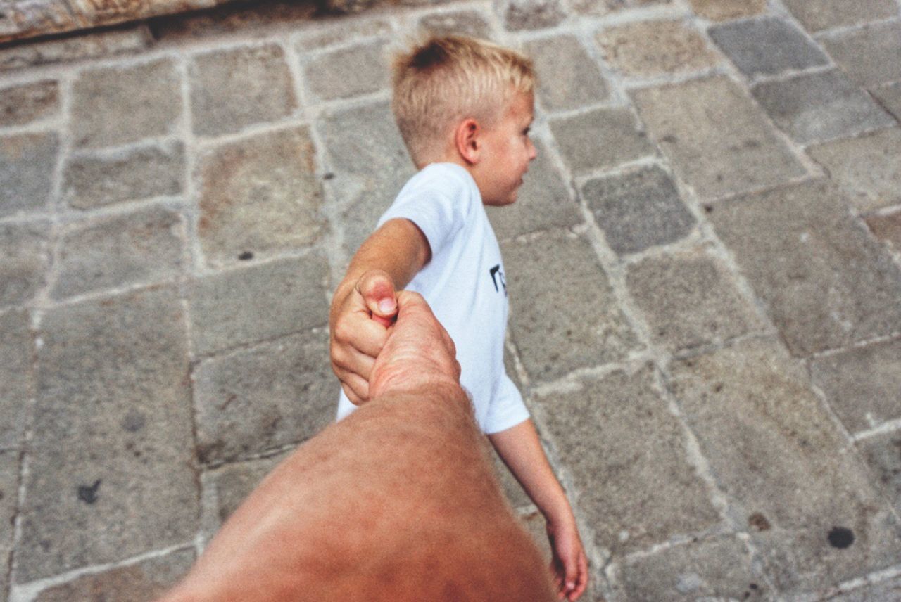 High angle view of boy pulling hand of father outdoors