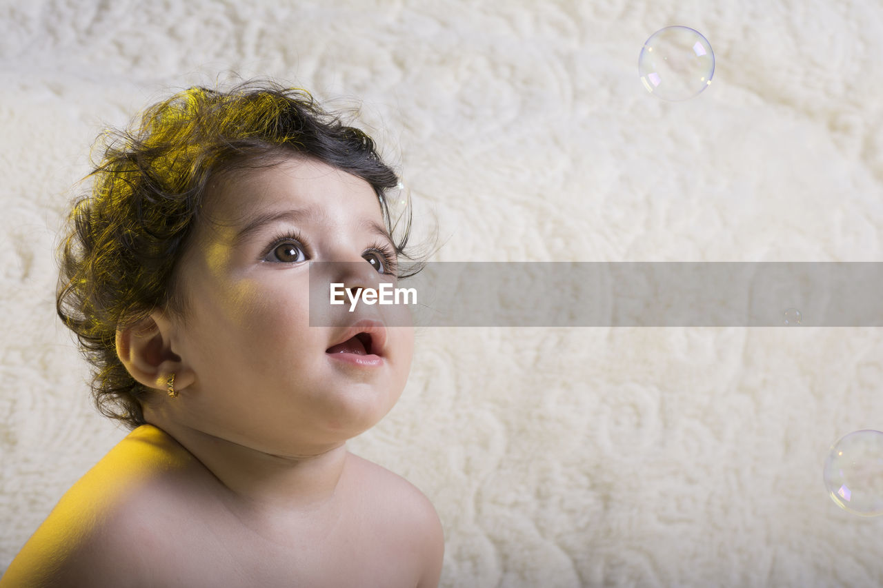 Close-up of cute girl looking at bubbles