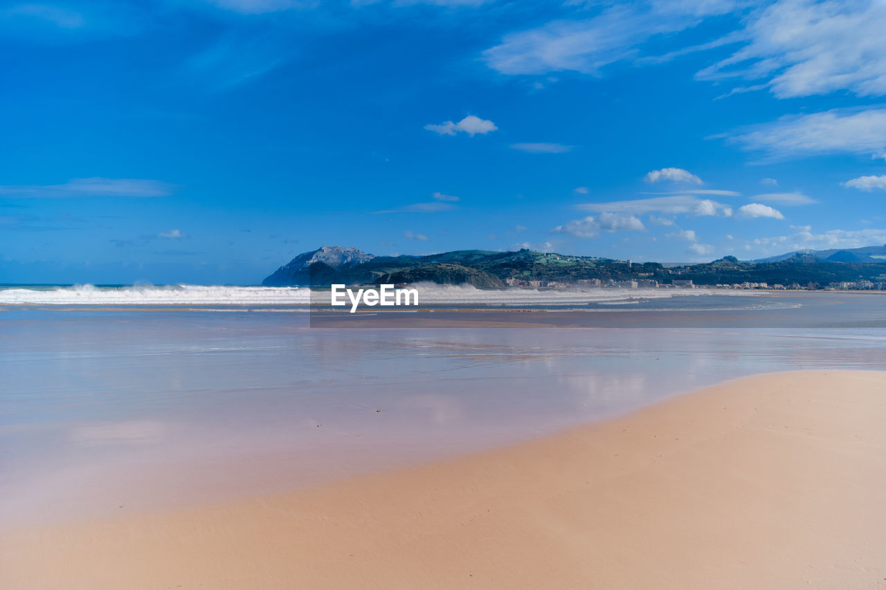 Scenic view of beach against blue sky