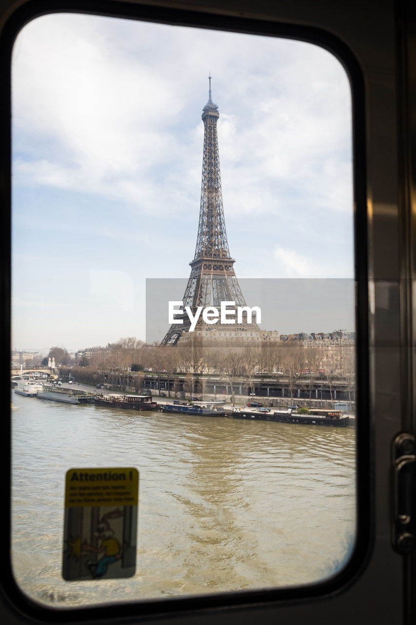 architecture, travel destinations, built structure, travel, city, sky, reflection, tourism, water, transportation, nature, cloud, tower, window, mode of transportation, river, building exterior, no people, cityscape, day, outdoors, landmark, metal, picture frame, vehicle interior, blue, vacation, building, history, city life, nautical vessel