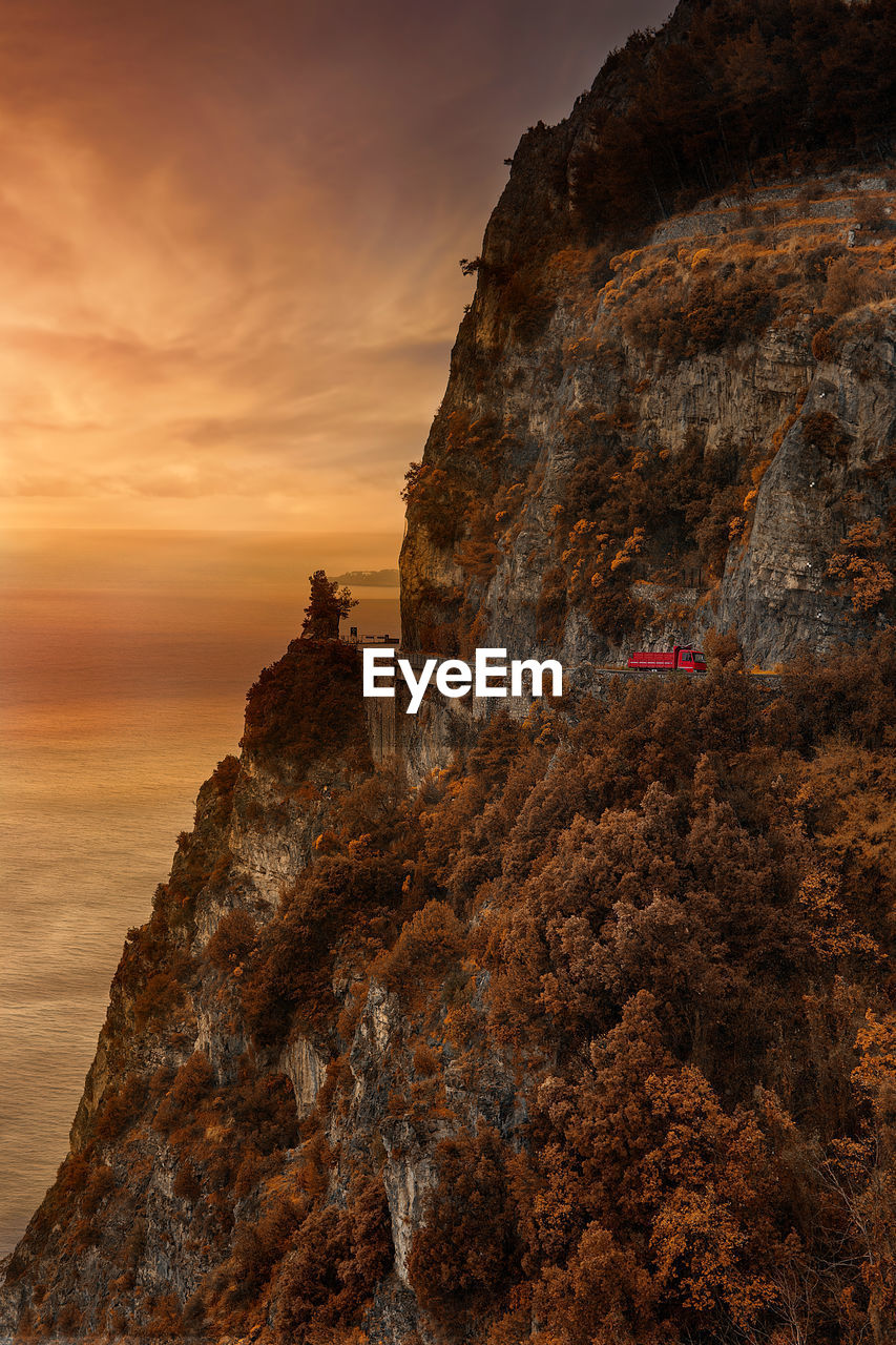 Rock formations by sea against sky during sunset