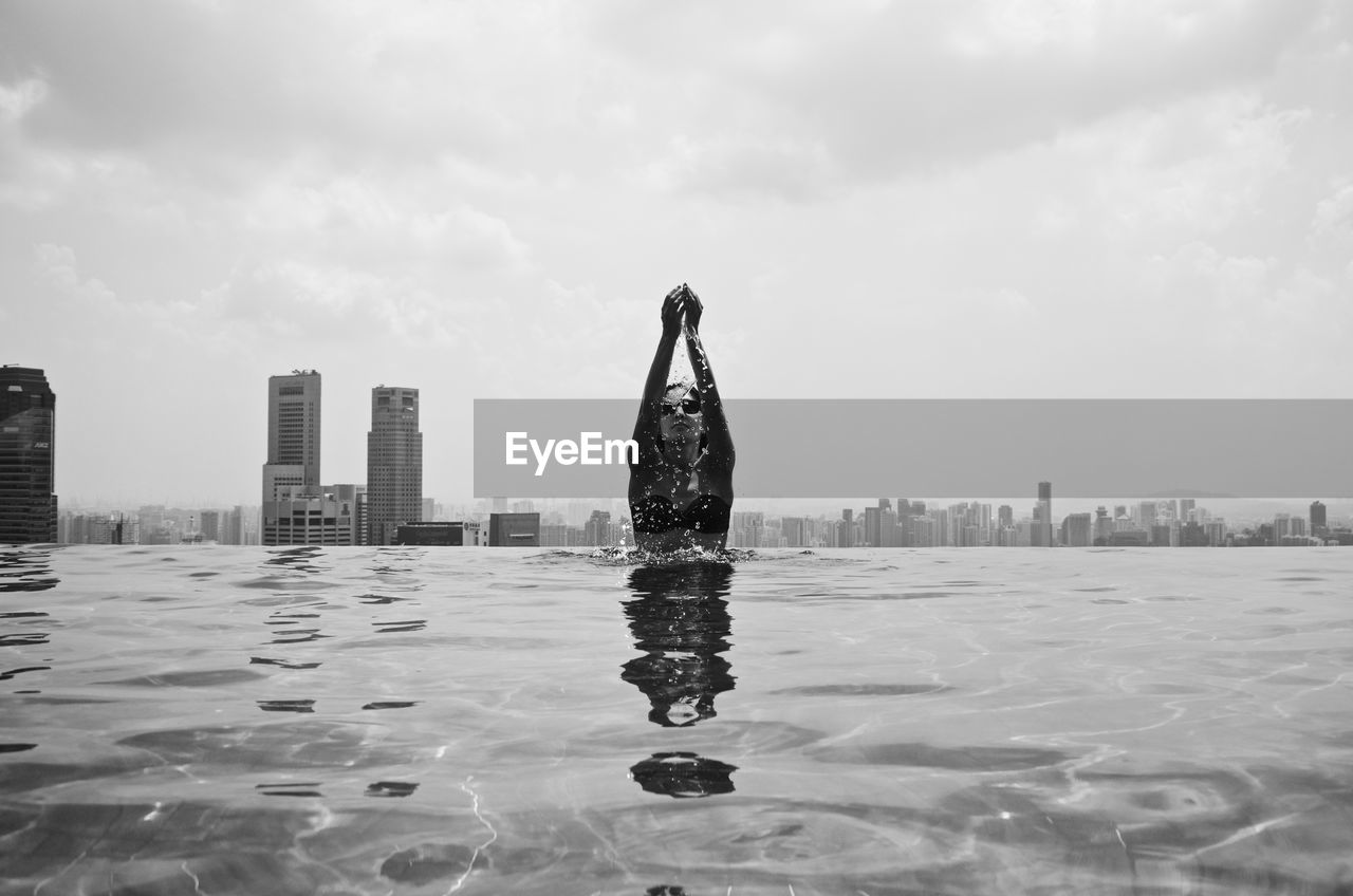 Woman swimming in infinity pool against sky