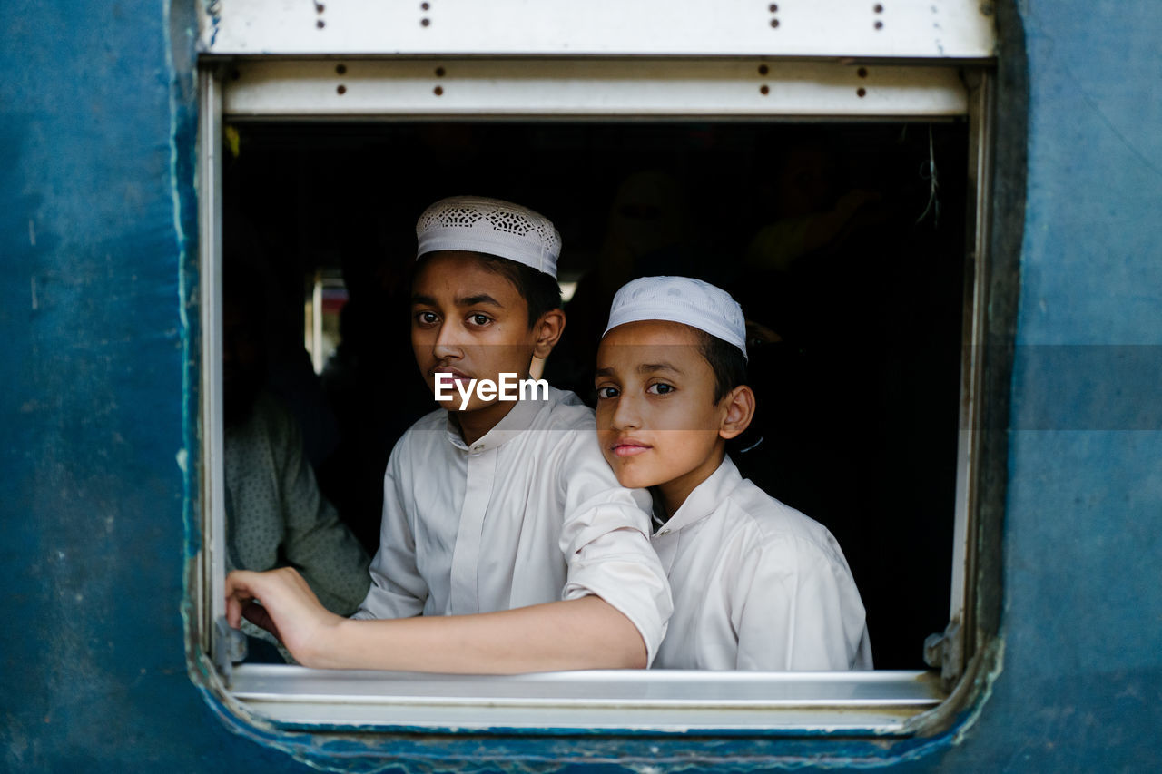 PORTRAIT OF A SMILING BOY SITTING ON WINDOW