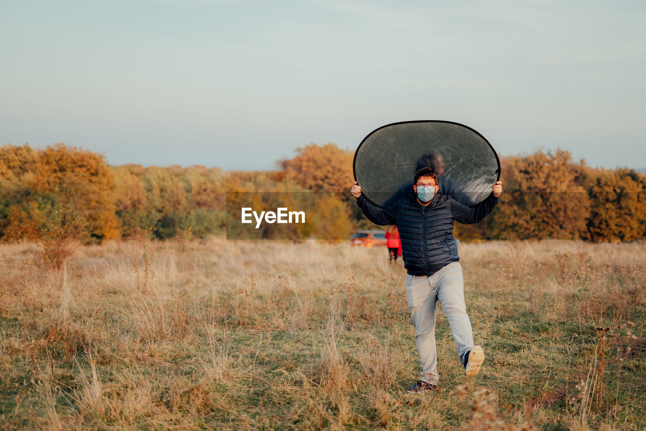 Full length of man photographer standing on field against sky