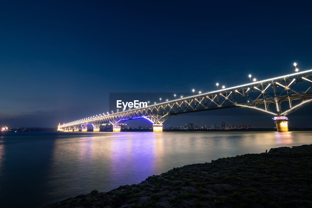 Low angle view of illuminated bridge over river at night