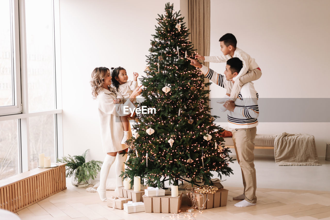 An asian multi-racial family with two children celebrate the christmas holiday in a decorated indoor