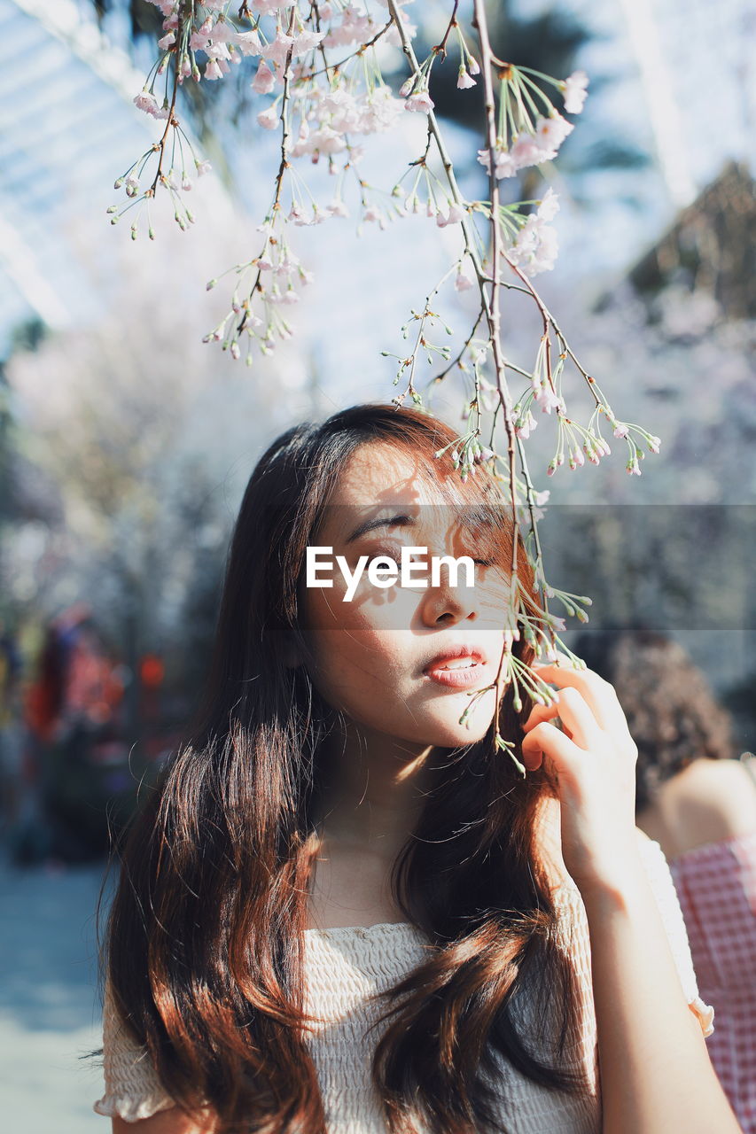 Close-up of young woman holding flower buds while standing at park