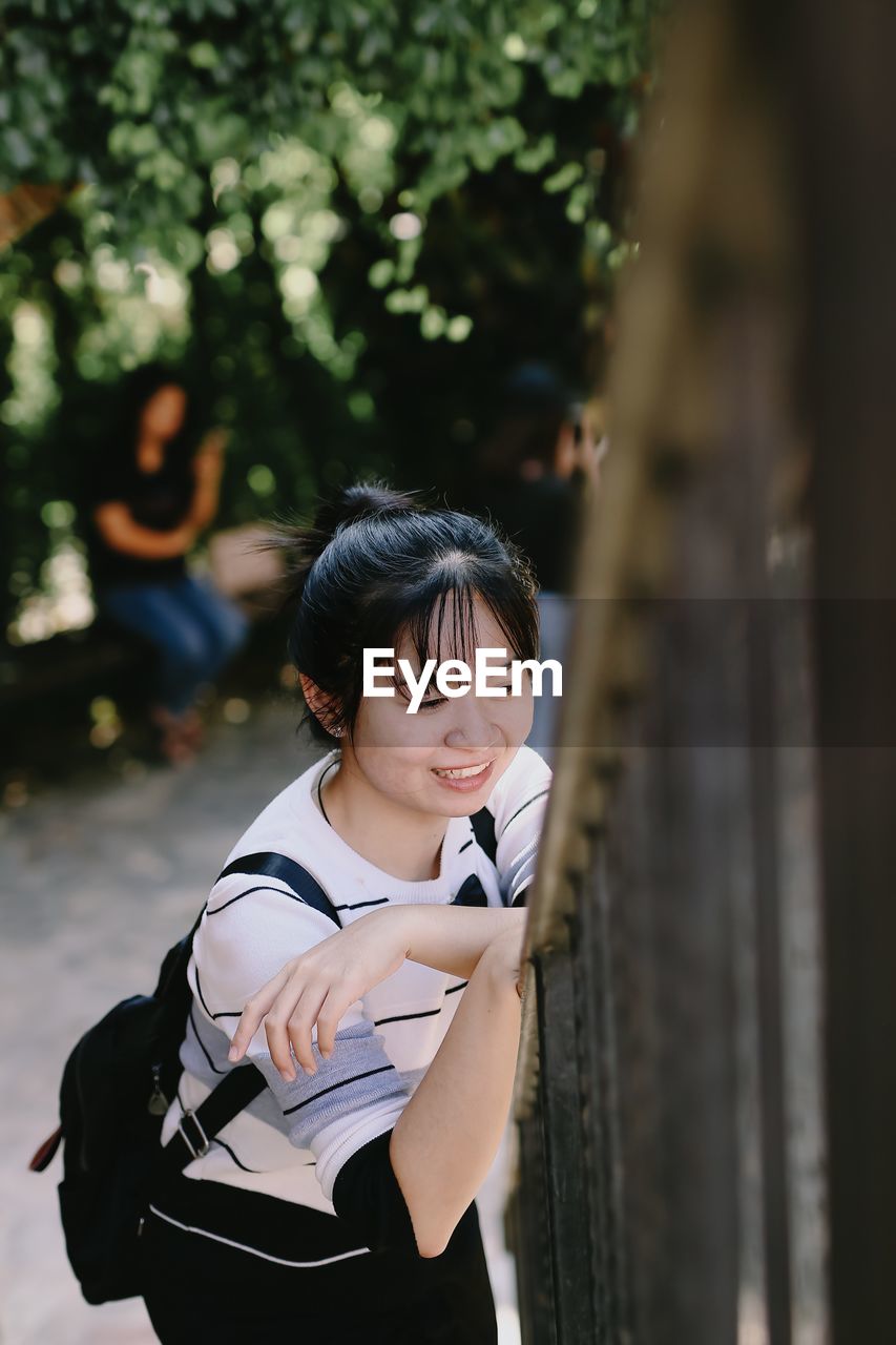 PORTRAIT OF BEAUTIFUL YOUNG WOMAN STANDING AGAINST BLURRED BACKGROUND