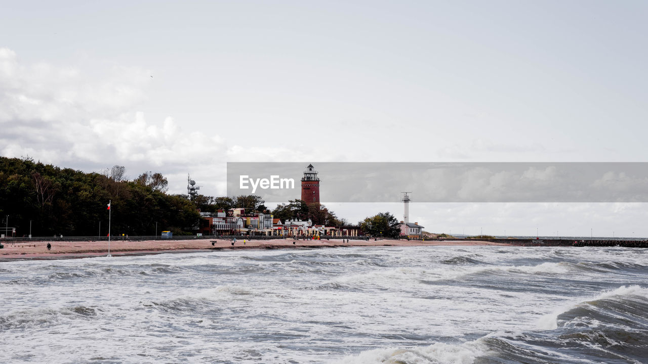 Scenic view of sea by buildings against sky