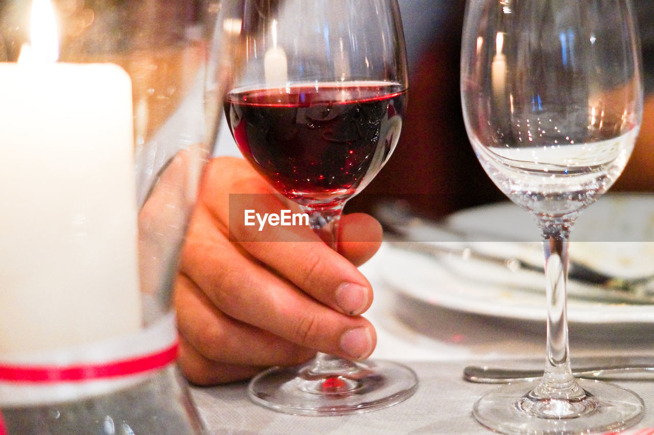 Midsection of woman holding wine glass on table