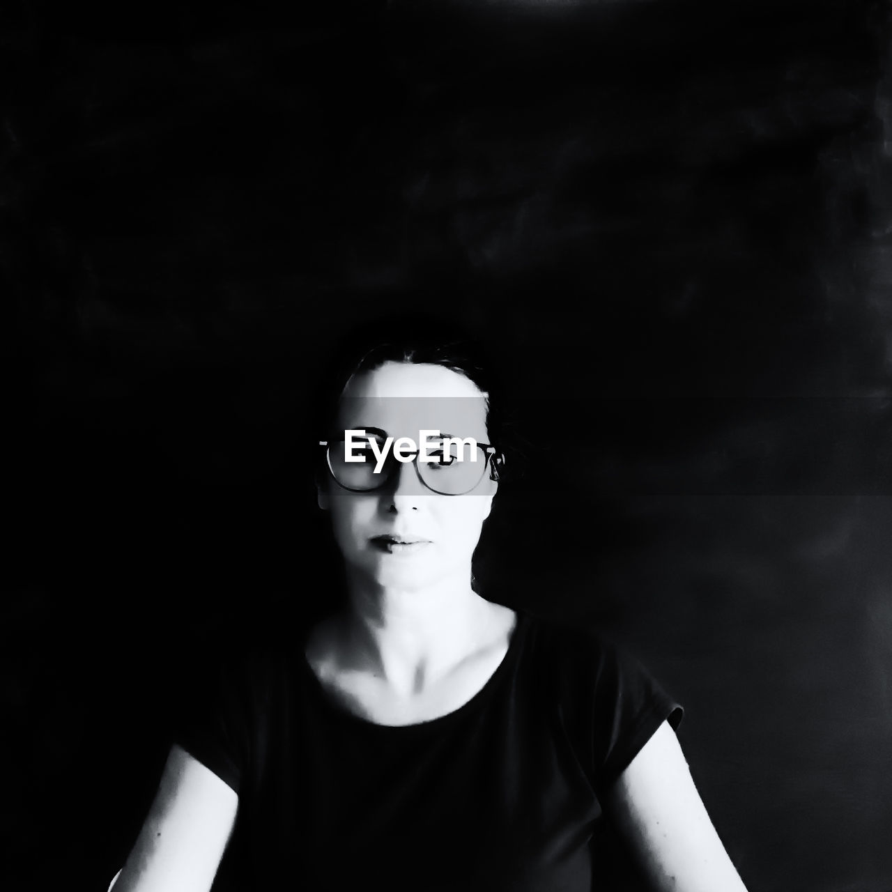 PORTRAIT OF YOUNG MAN WITH EYEGLASSES IN BLACK BACKGROUND