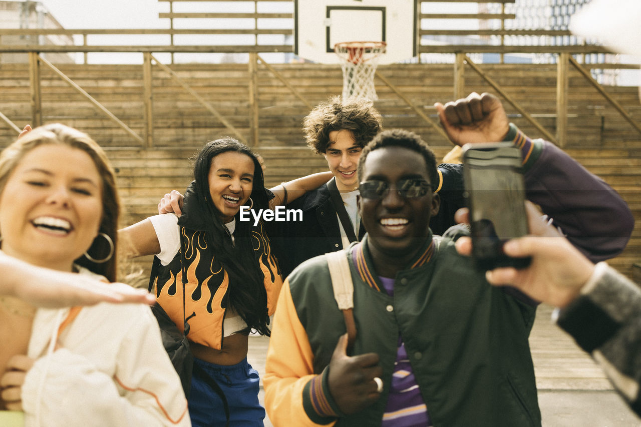 Cheerful male and female friends enjoying while dancing in basketball court