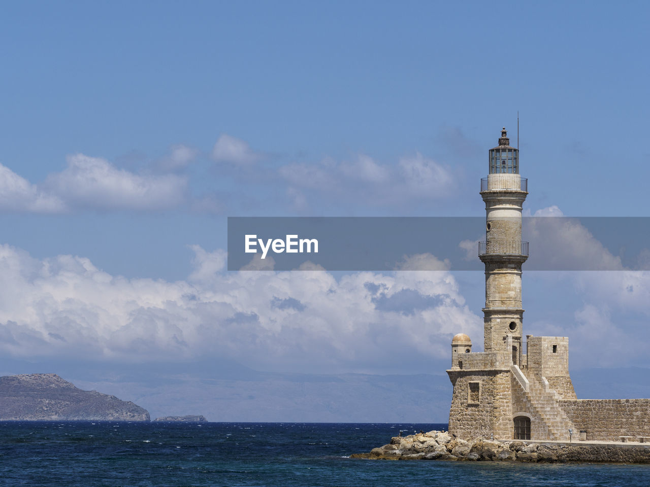 Lighthouse at old venetian harbour in sea against sky