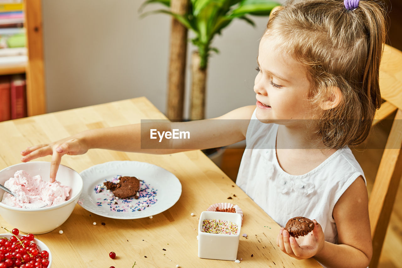 High angle view of girl eating muffin at home