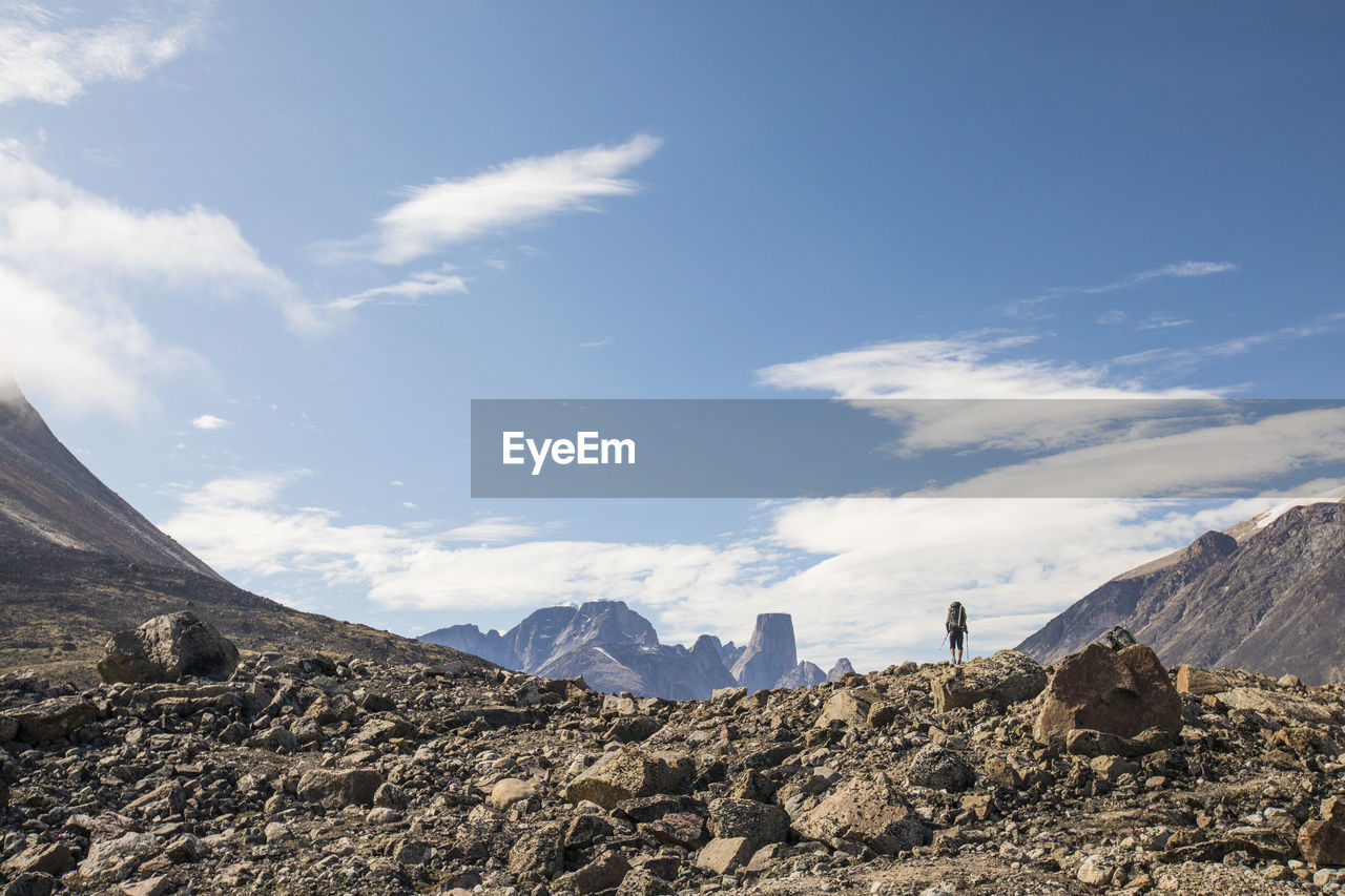 Hiker on distant mountain ridge looking at mountain view.