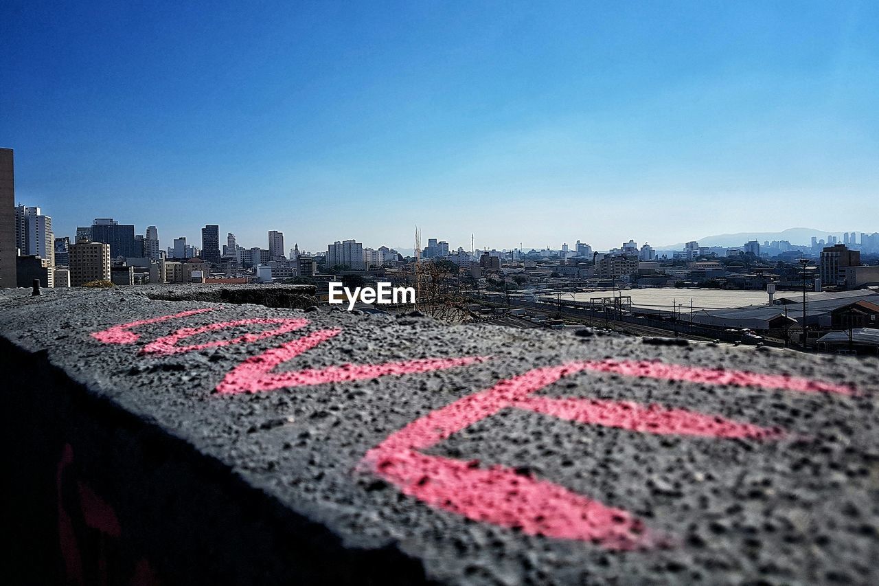 Love text on retaining wall against clear blue sky during sunny day