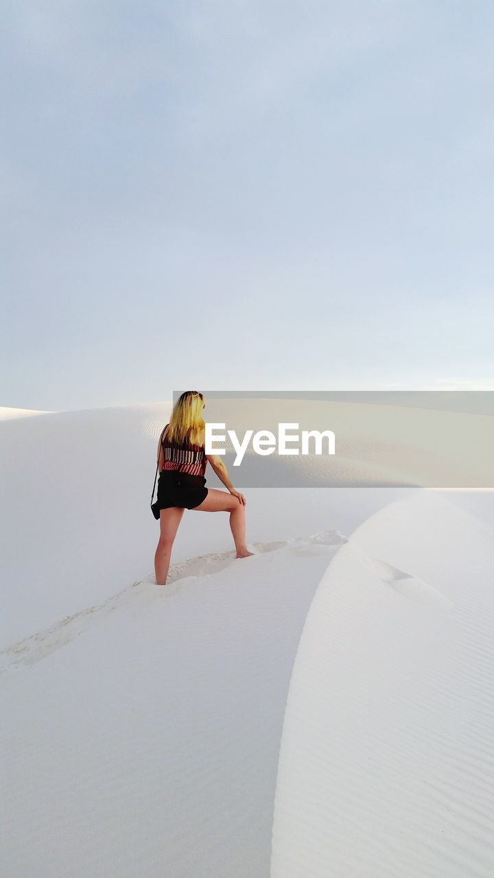 Woman standing on sand at beach against sky