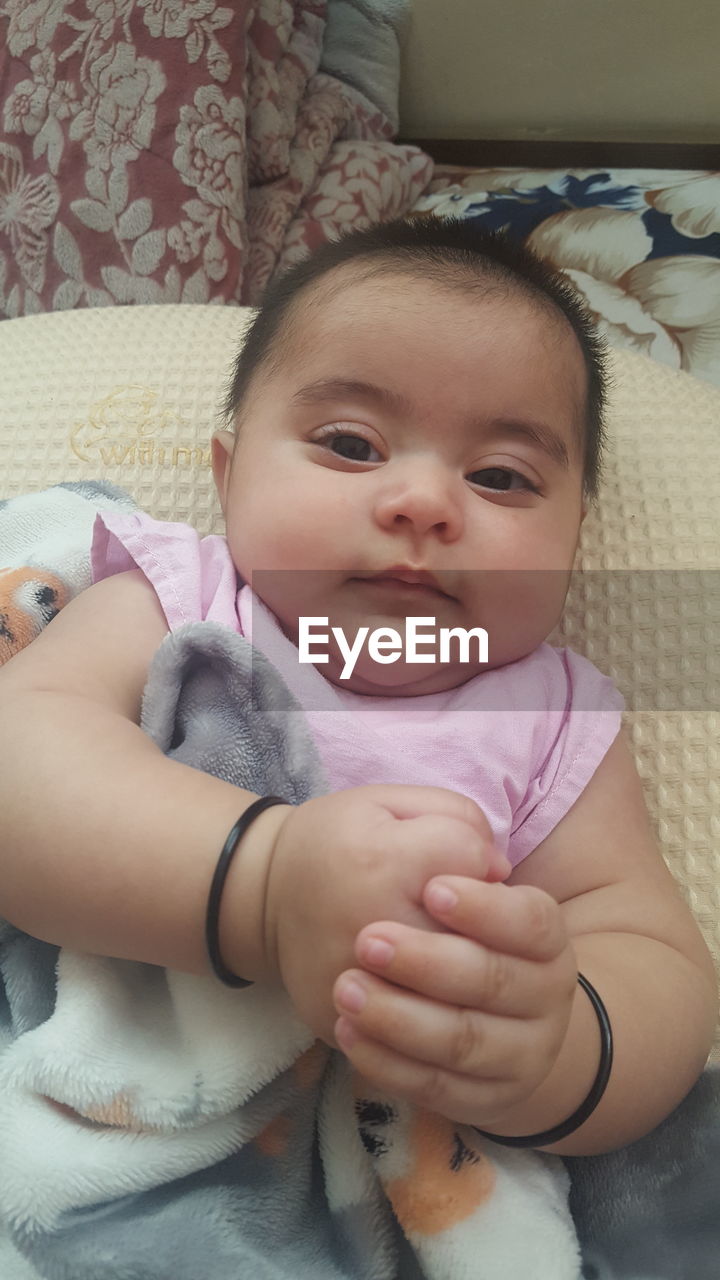 PORTRAIT OF BABY GIRL LYING ON SOFA