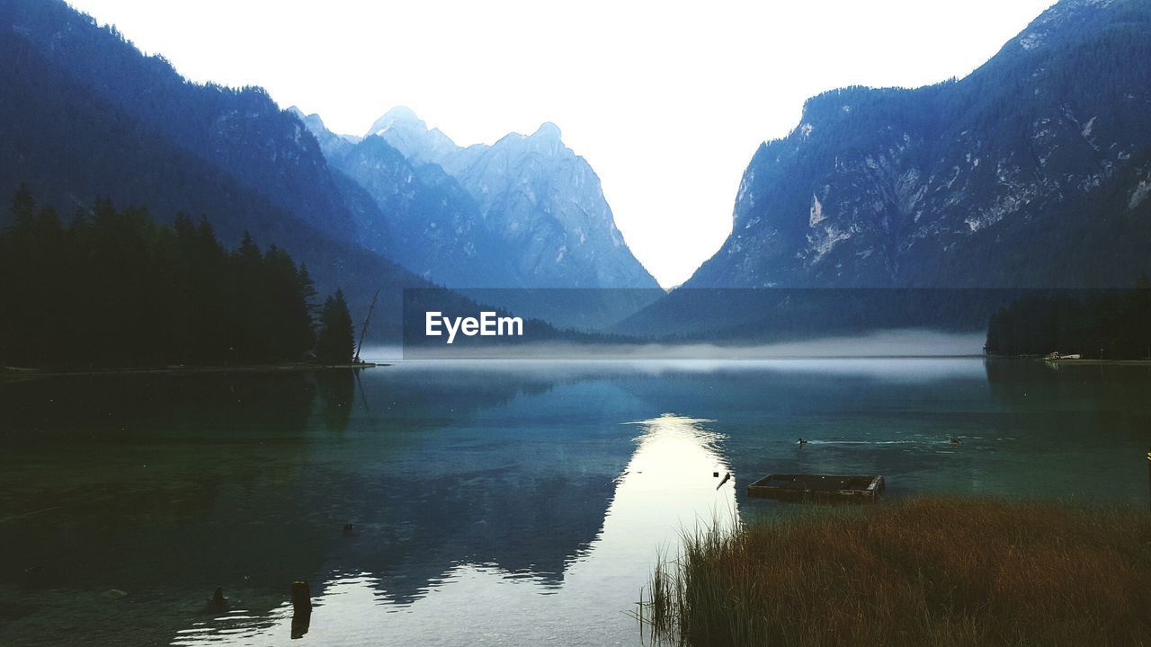 SCENIC VIEW OF CALM LAKE AGAINST MOUNTAIN RANGE