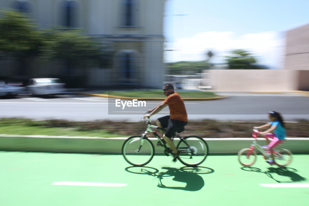 Blurred motion of father and daughter riding bicycle