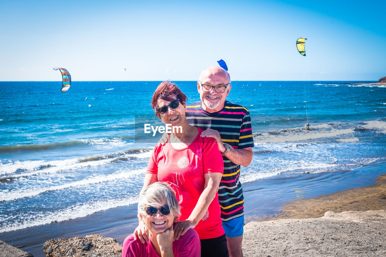 Portrait of friends enjoying at beach against sky