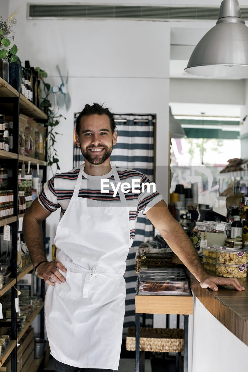 Portrait of smiling male entrepreneur with hand on hip in bakery