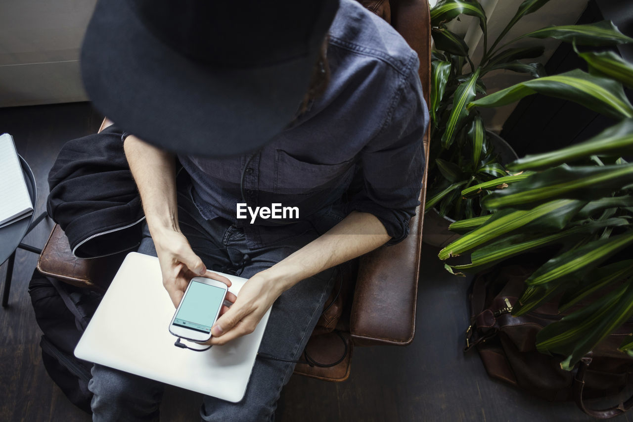 High angle view of blogger using phone while sitting on chair