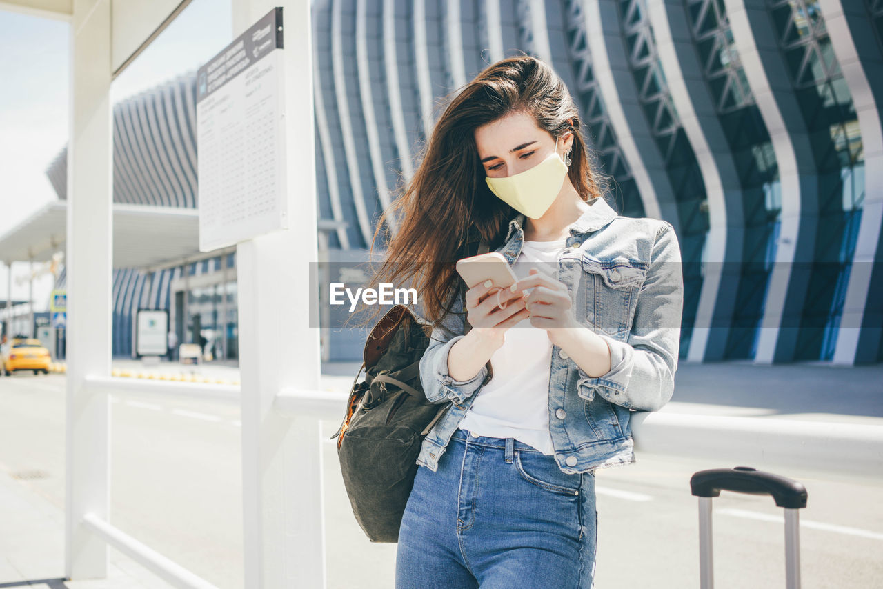 portrait of young woman using mobile phone while standing outdoors