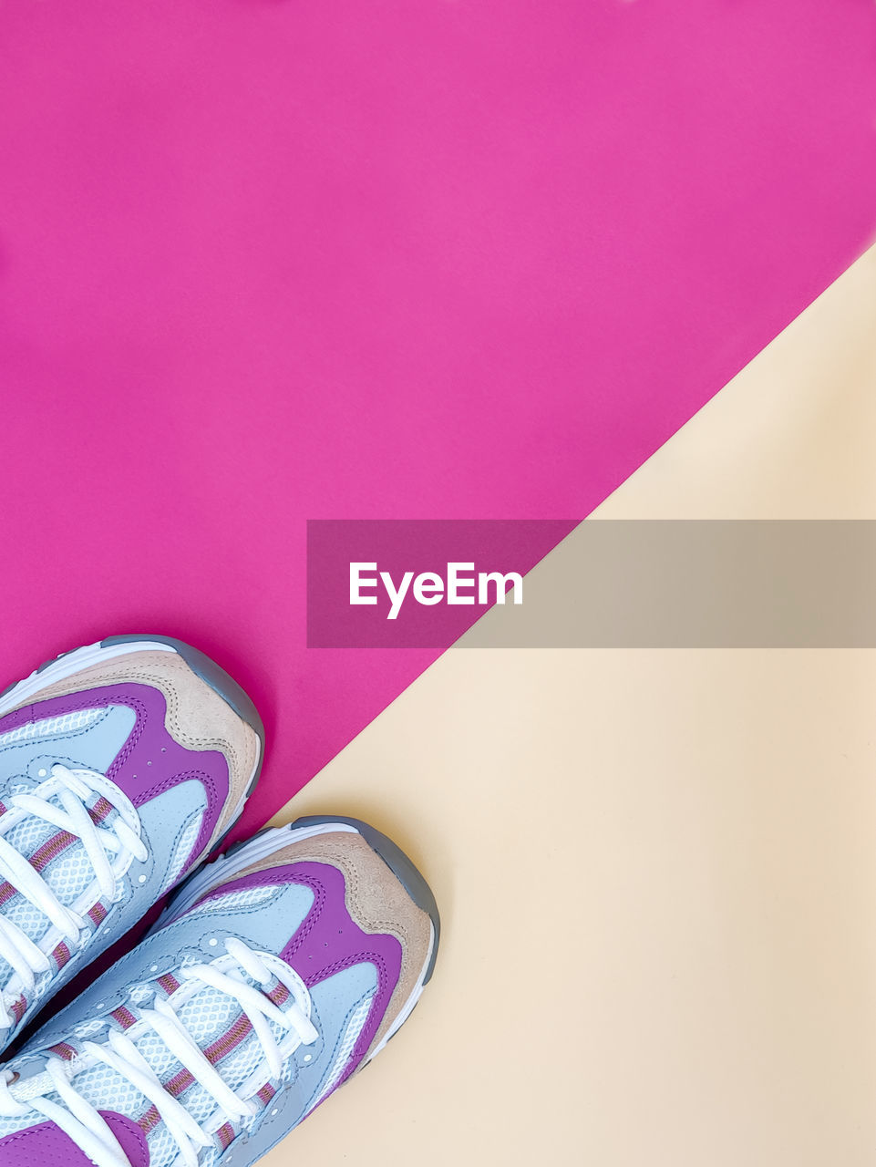 Pair of new stylish sneakers on a pastel orange and bright pink background, copy space