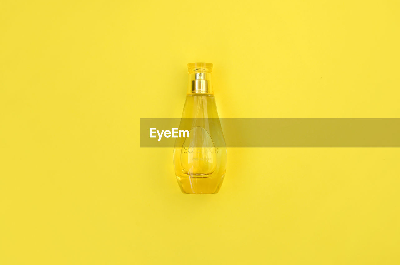 CLOSE-UP OF YELLOW BOTTLE IN GLASS OVER WHITE BACKGROUND