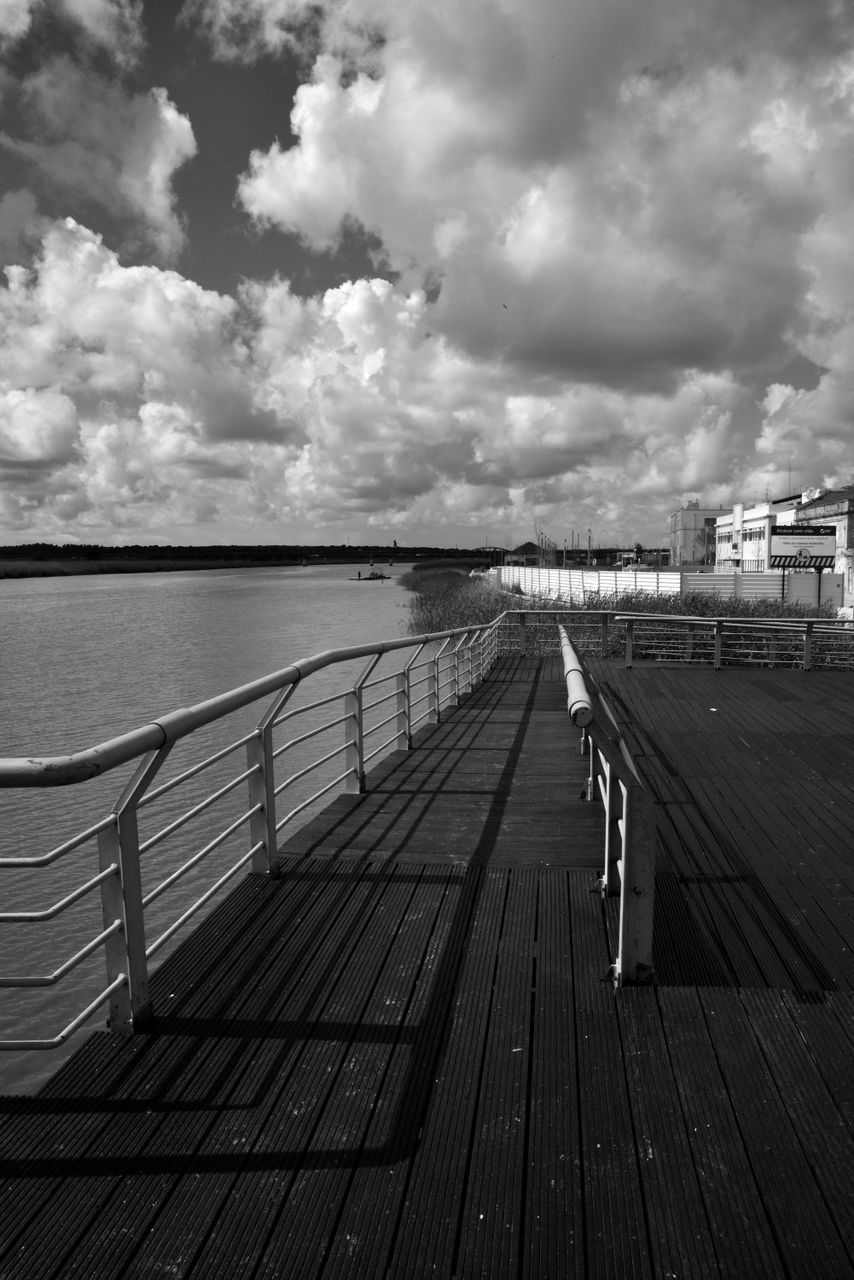 BOARDWALK LEADING TOWARDS WATER AGAINST SKY