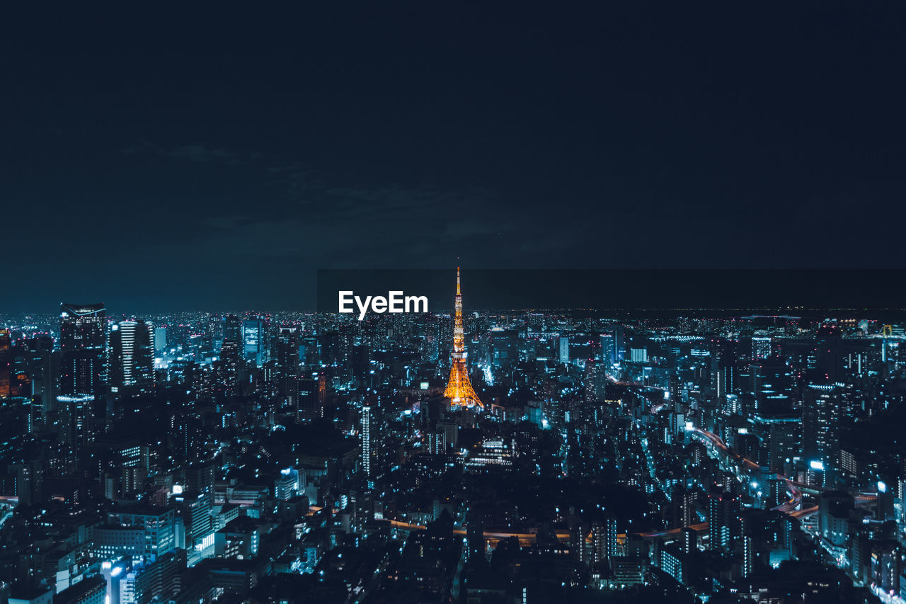 Illuminated tokyo tower amidst buildings against sky at night