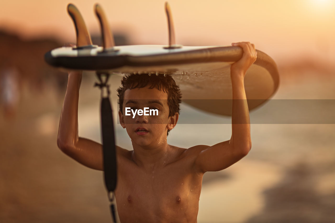 Rear view of shirtless man with surfboard
