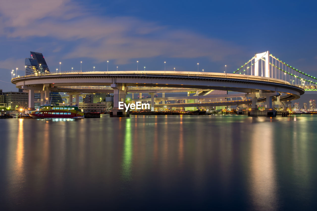 Bridge over river against sky in city at night