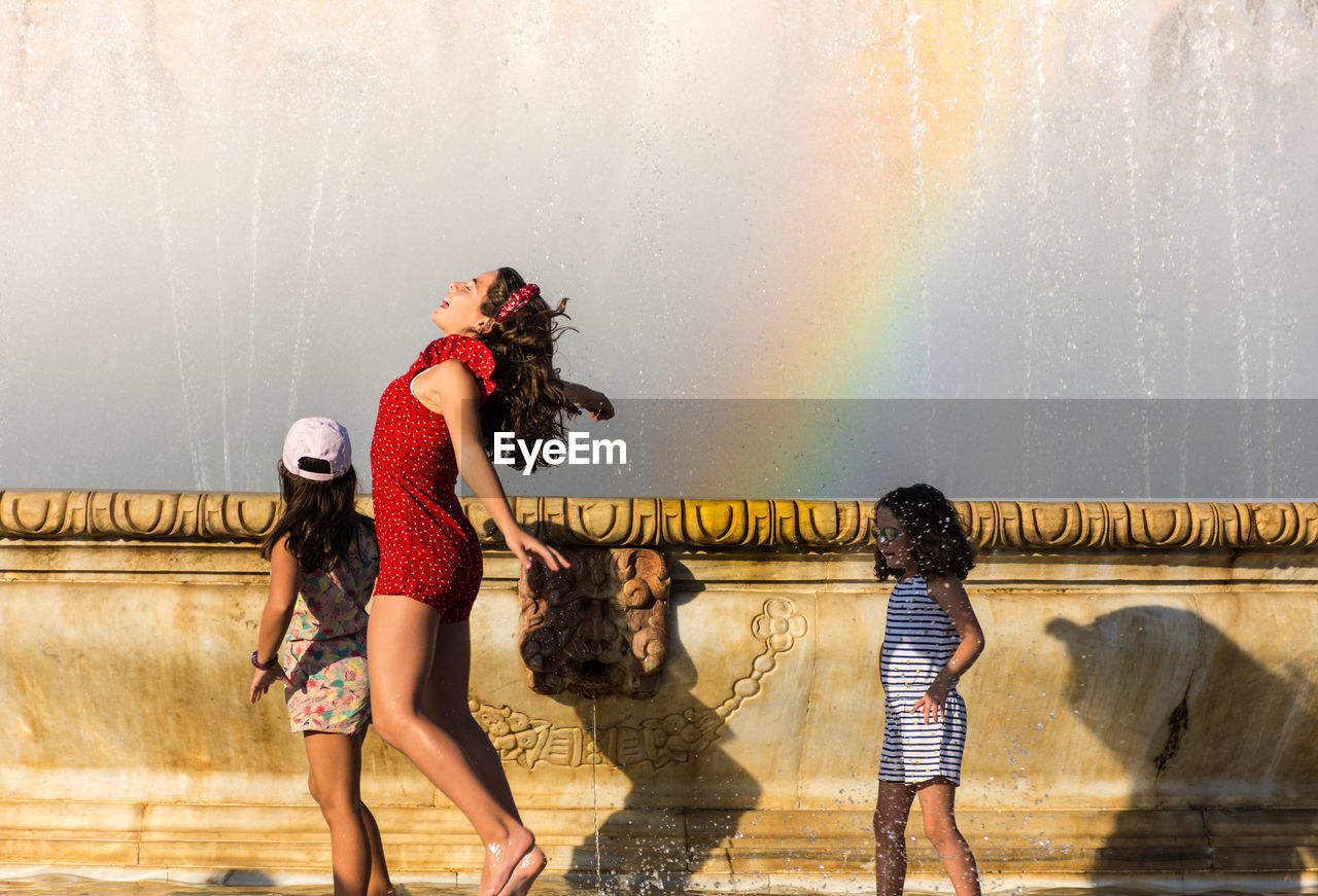 FULL LENGTH OF WOMAN WITH ARMS RAISED AGAINST WATER