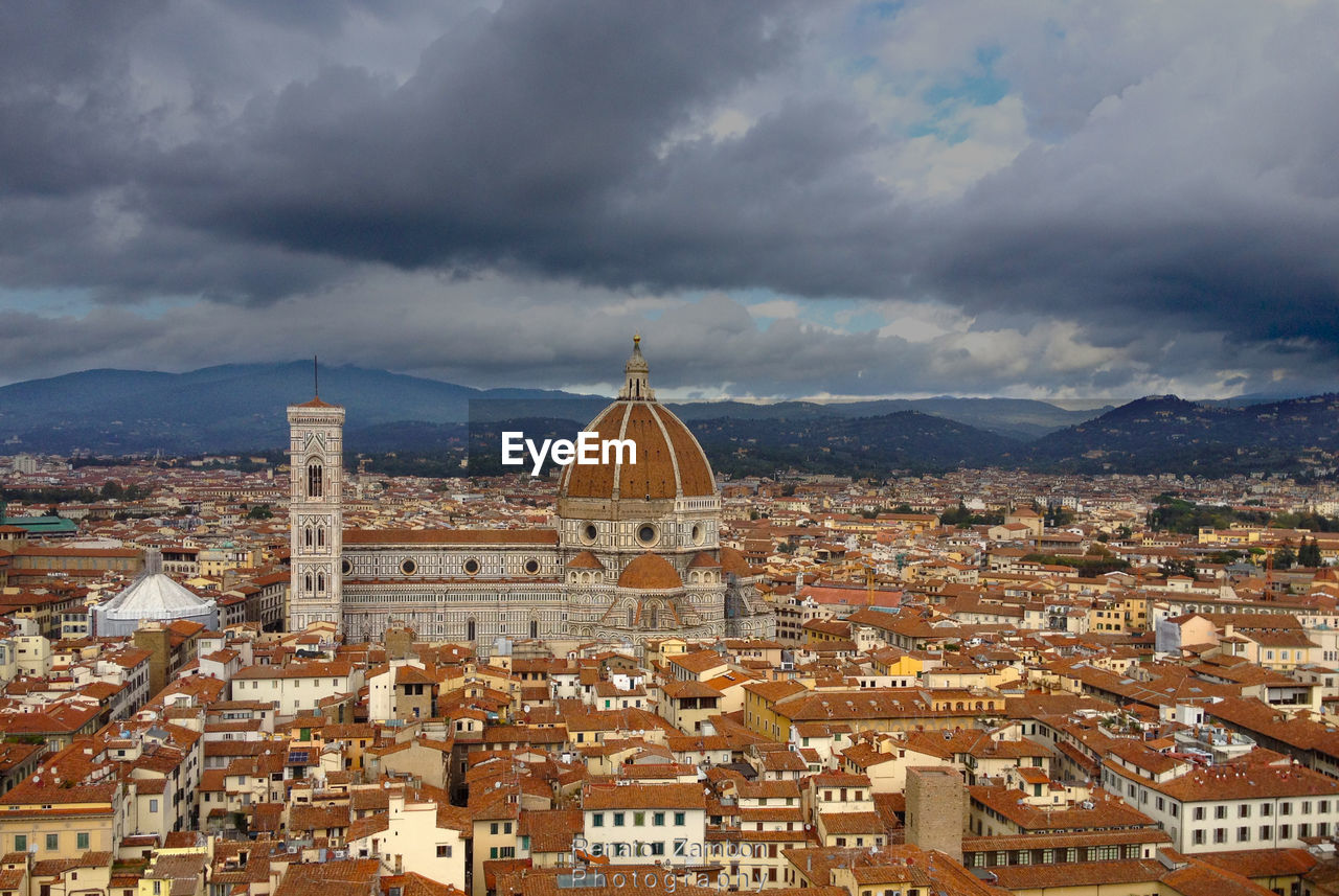 View of cityscape against cloudy sky