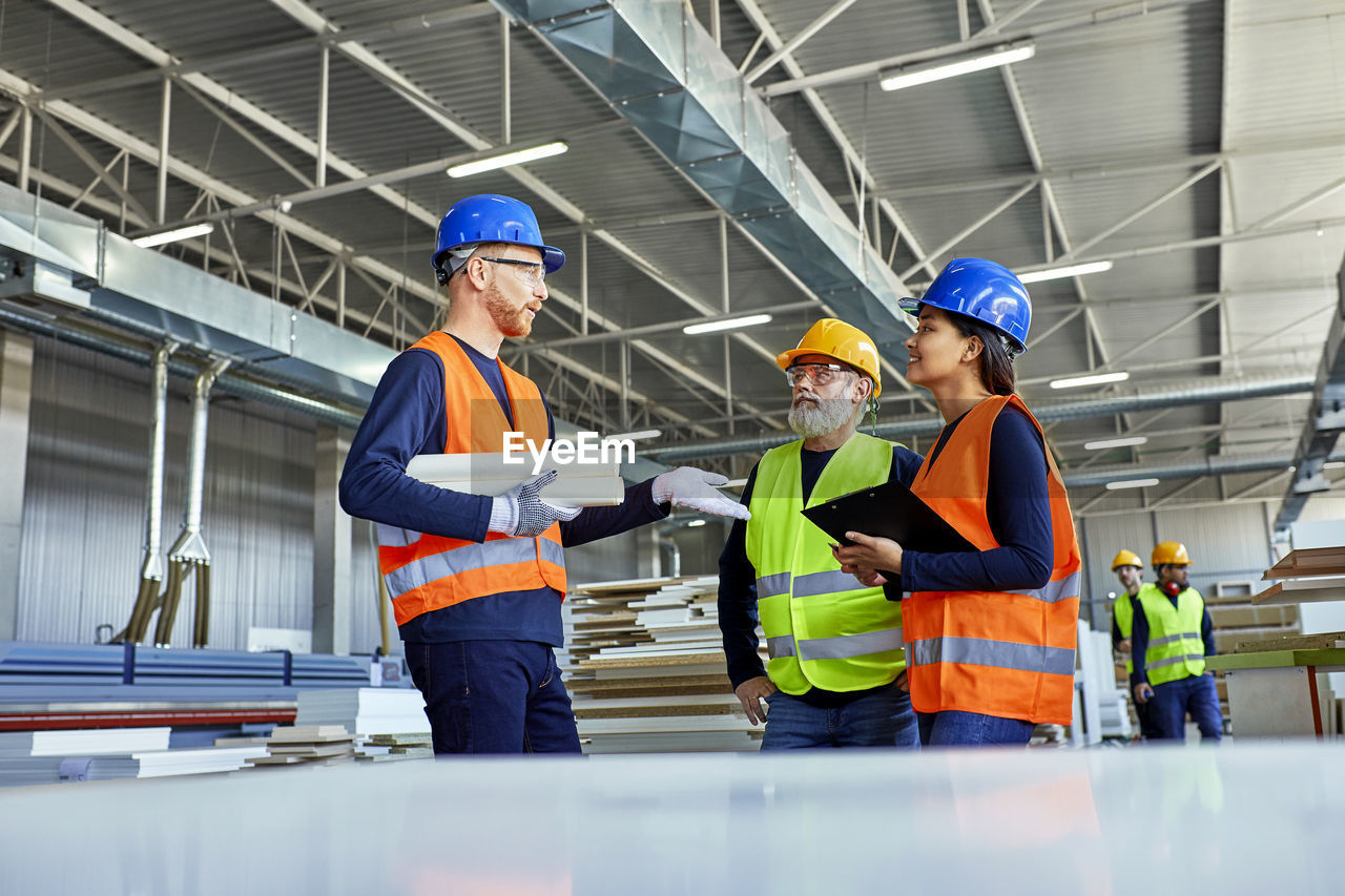 Colleagues in protective workwear talking in factory