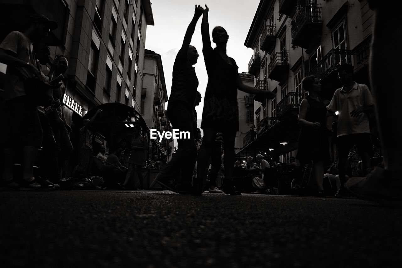 Low angle view of silhouette men and women dancing on street