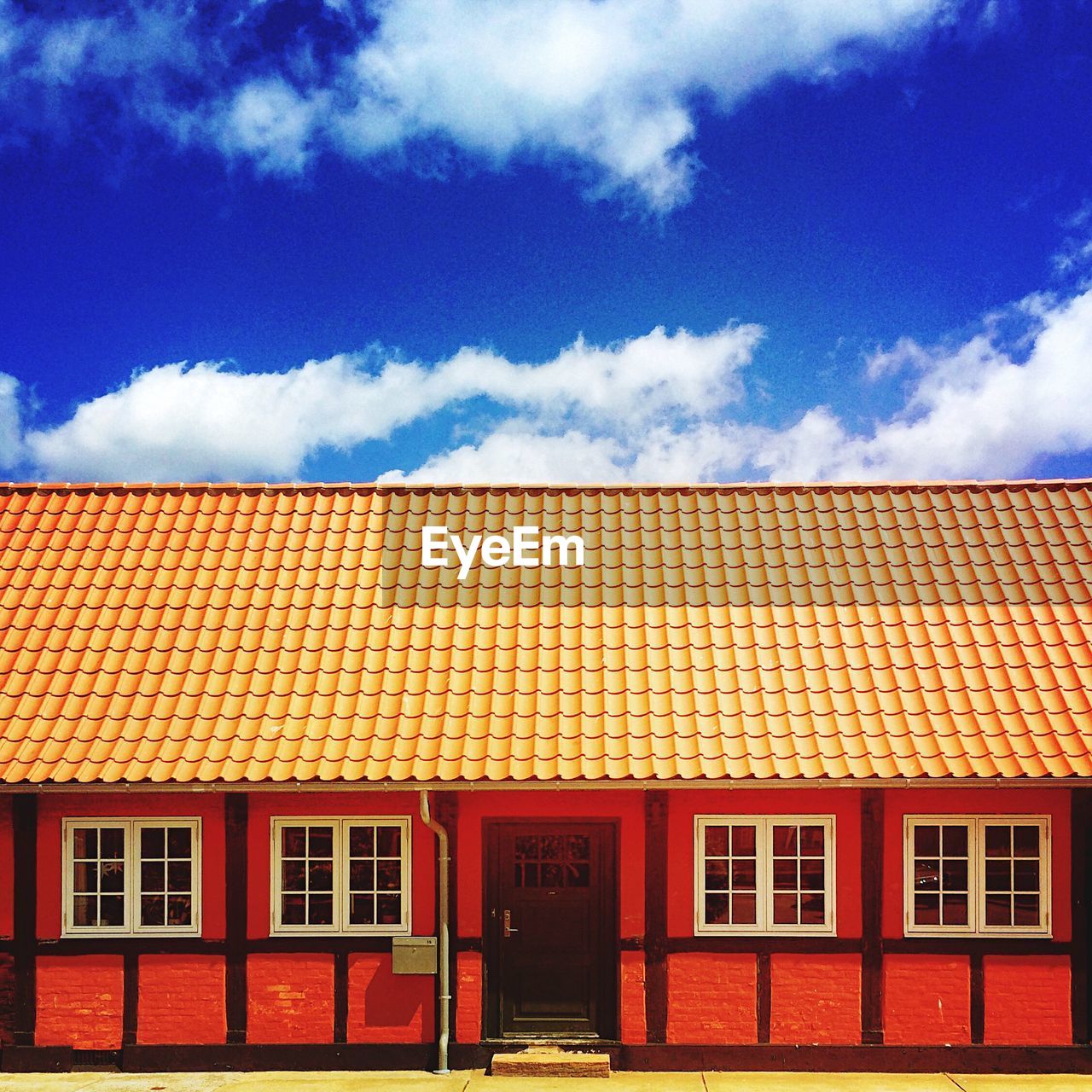 Red house against cloudy blue sky